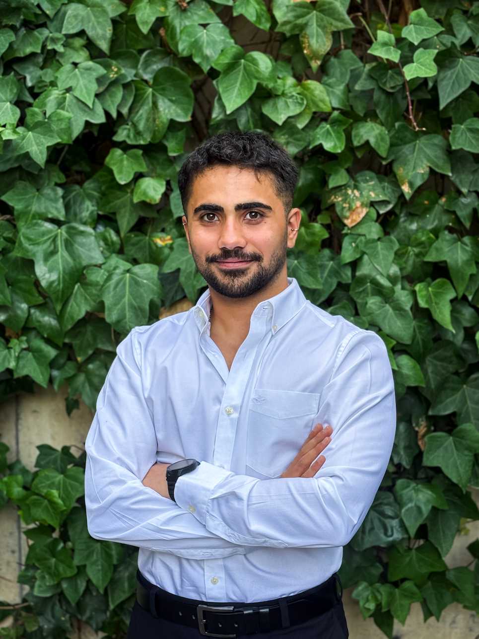 Emre Kent standing in front of a wall of ivy